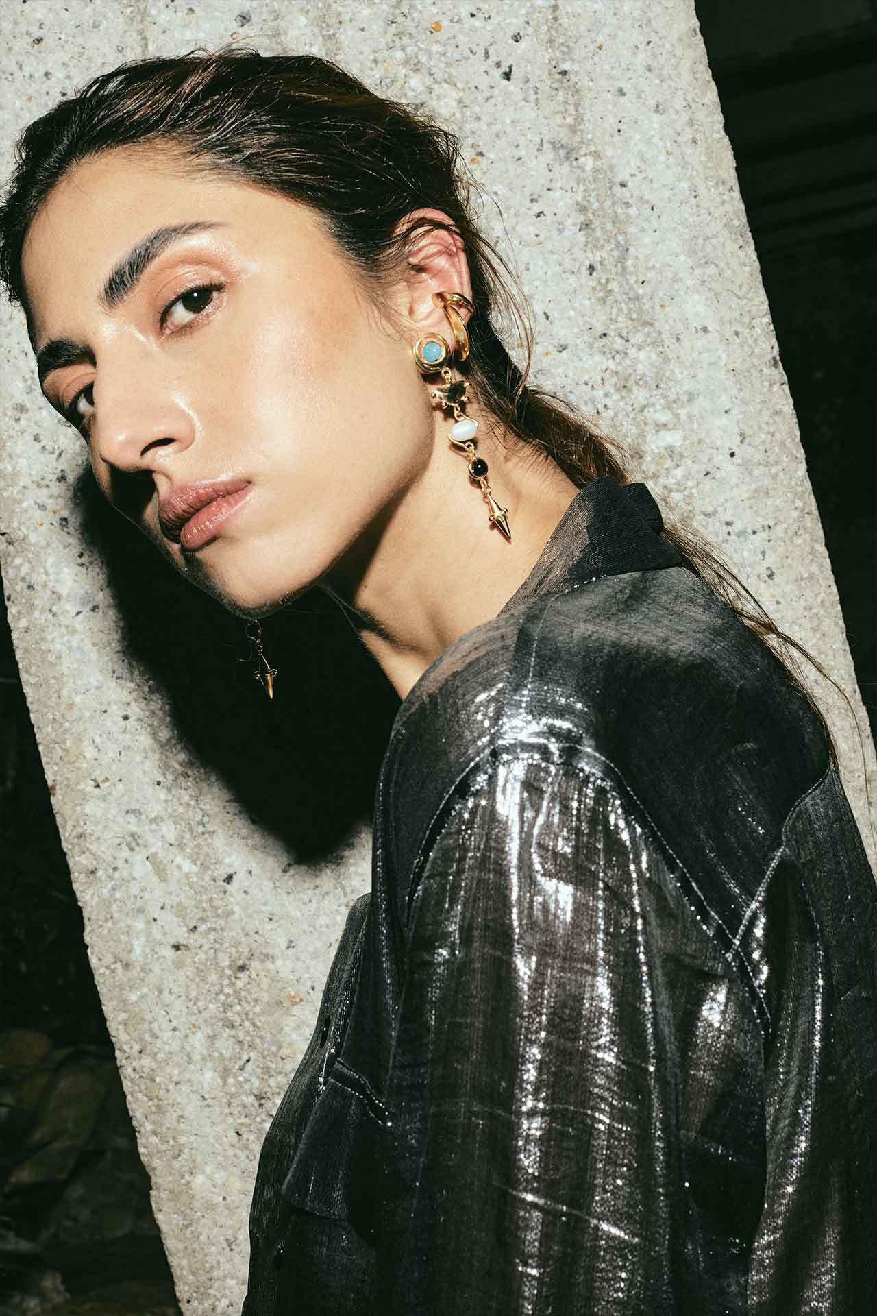 juana del rio con dos ear cuffs y unos aretes largos dorados que representan las fases lunares y una camisa brillante de plata. Hecho en plata reciclada por la diseñadora de joyas pakistaní-colombiana aysha bilgrami en Bogotá, colombia