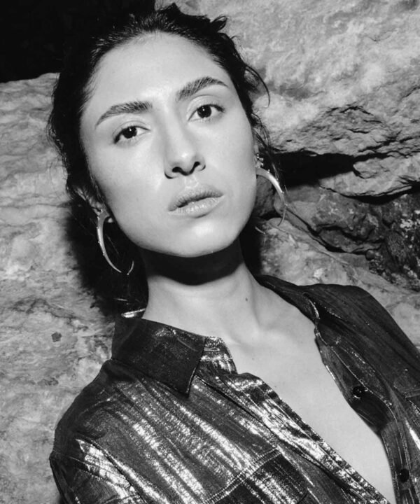 portrait of juana del rio wearing a silver shirt and large crescent hoops