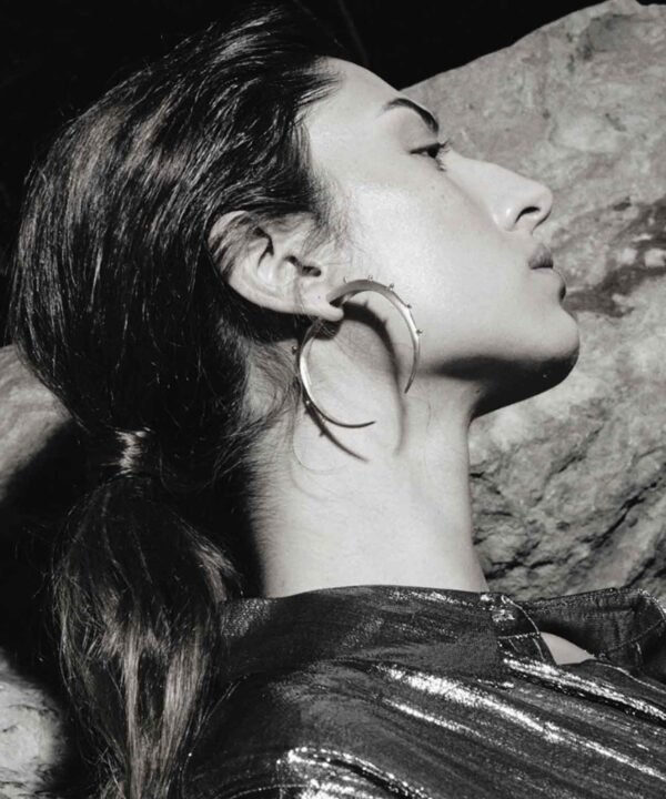 side shot of a lady wearing a silver shirt and large crescent hoop earrings Made by aysha bilgrami in recycled silver in bogota colombia
